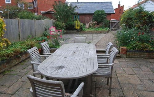 There is plenty of seating in the attractive garden.  The path leads to the garage and parking for up to four cars.