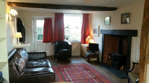 Sitting room area with inglenook, beams, wood-burner feature, TV, DVD player, CD player and board games.